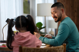 father working in home office next to his daughter